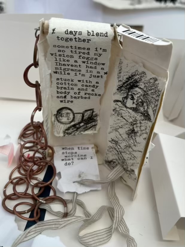 A tall thin medicine box has been cut open and had a chunky copper chain attached. Inside the box are three pieces of paper. The first on the upper left side read in neatly typed text “the days blend together, sometimes I’m so tired my vision foggs like a window. I haven’t had a migraine in a while I’m just stuck with a cotton candy brain and a body of rocks and barbed wire”. The bottom of the piece of paper has a black and white drawing of an alarm clock and open pill organiser. The lower left paper, which is more tattered than the other, reads “when time stops working what can I do”? The last piece of paper on the right has another black and white drawing of a figure in bed with the cover pulled up over their chin. The figures eyes look off to the side and their face looks worried.