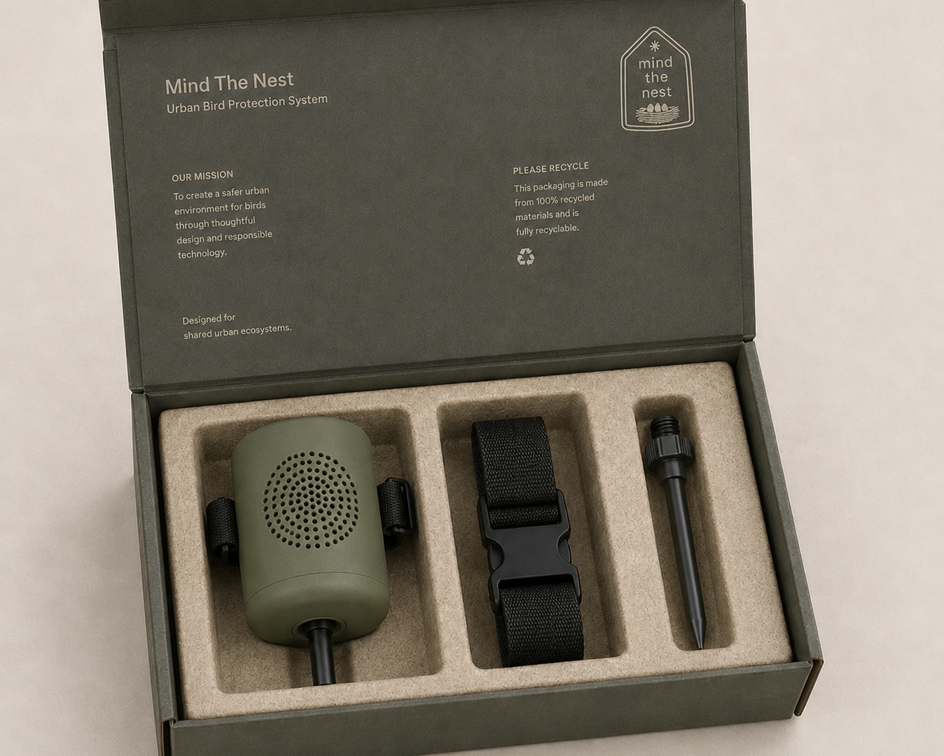 Minimal packaging design for the “Mind the Nest” urban bird protection system, showing the main device, adjustable tree strap, and ground stake arranged inside recyclable moulded pulp packaging with a muted olive-green colour palette.
