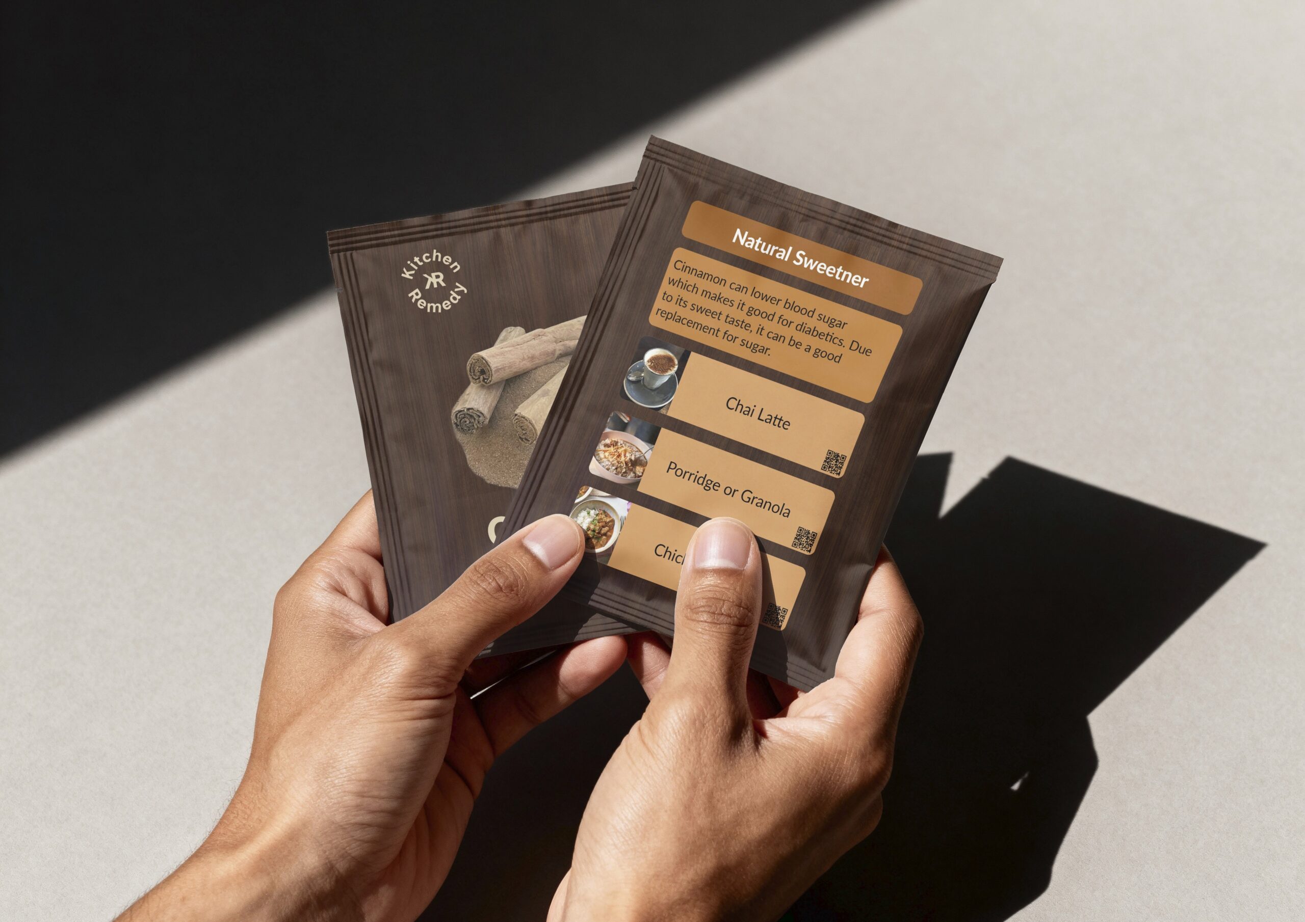 Someone holding two Kitchen Remedy packets which also shows the front and back of the cinnamon packets