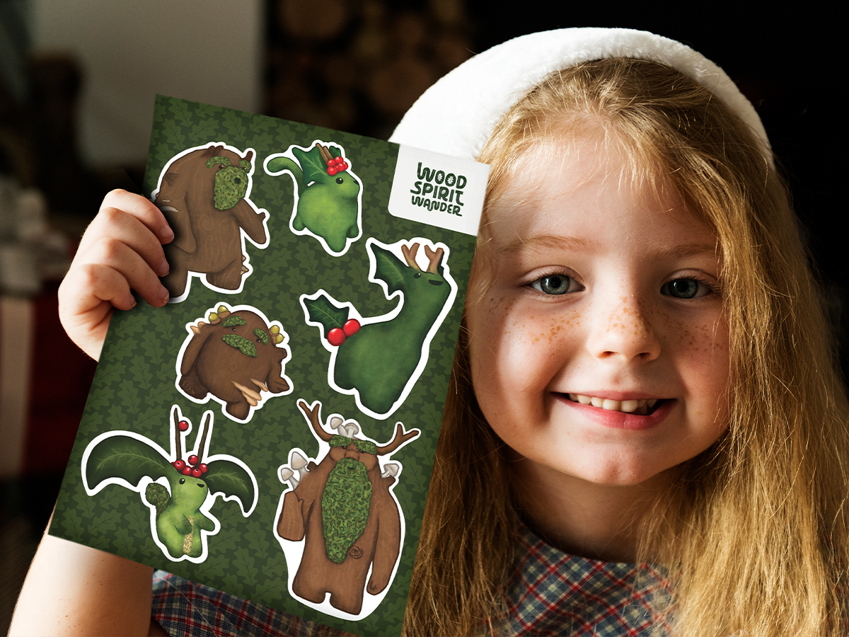 Little girls smiling and holding a sticker sheet of wood spirits.