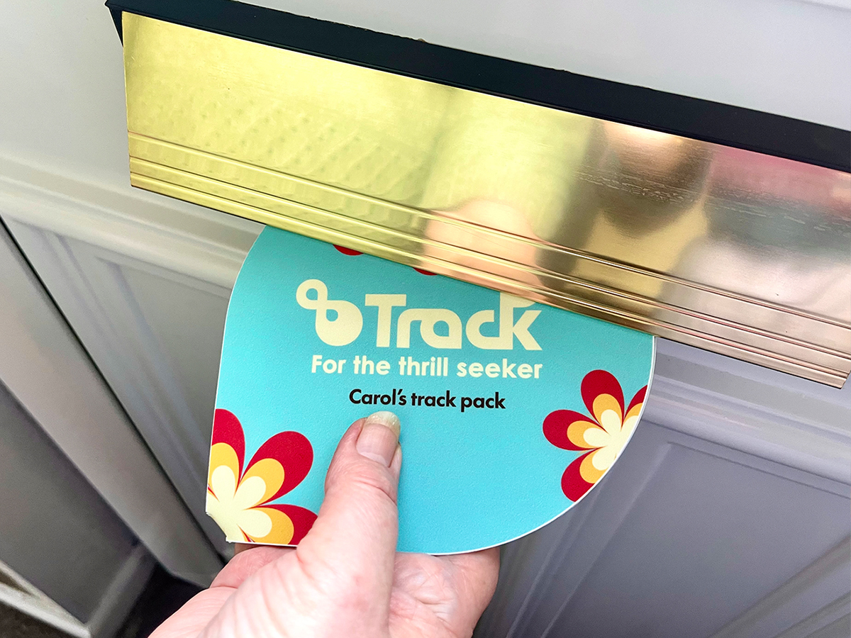 Track pack through a letter box. The pack is bright cyan with the logo an personalisation of 'Carol's track pack'.