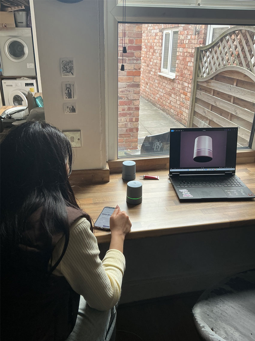 a participant sitting over a desk, looking at their phone with the prototypes in the background